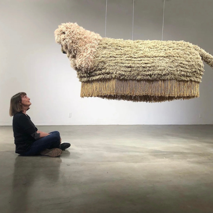 an artist sitting under her artwork
